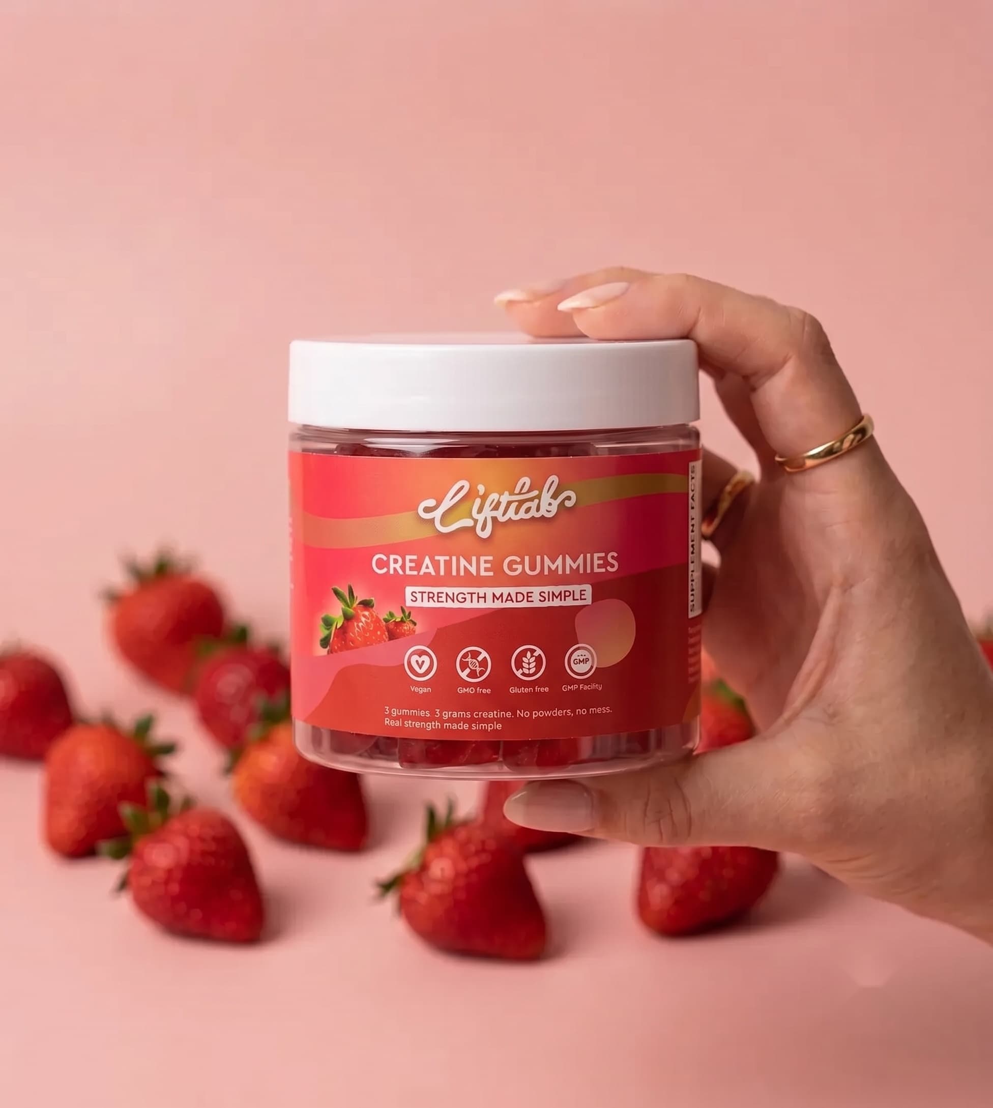 A hand holding a jar of LiftLab strawberry creatine gummies